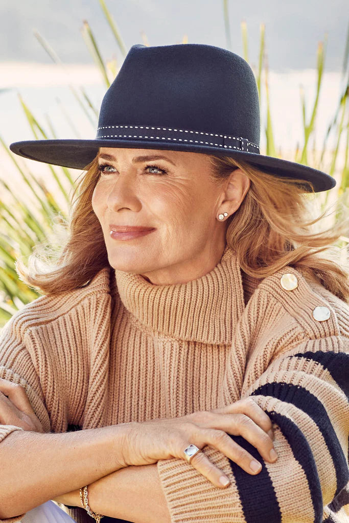 A black wool felt fedora with a wide flat brim, white feature stitching, and a grosgrain ribbon, offering UPF50+ sun protection and an adjustable fit.