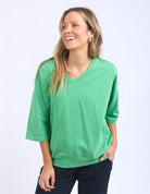 The Mazie Vee Neck in Greenbriar, a relaxed-fit cotton top with a spacious oversized design, features a flattering V-neckline, 3/4 length sleeves, and two front pockets, perfect for layering or casual wear