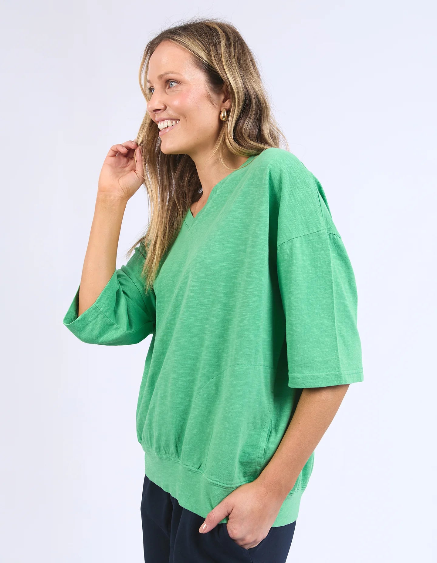 The Mazie Vee Neck in Greenbriar, a relaxed-fit cotton top with a spacious oversized design, features a flattering V-neckline, 3/4 length sleeves, and two front pockets, perfect for layering or casual wear