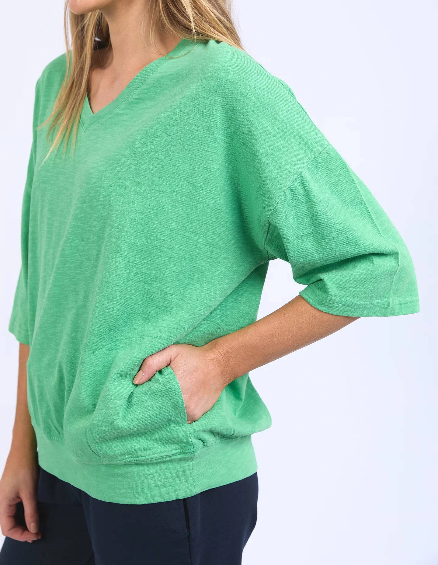 The Mazie Vee Neck in Greenbriar, a relaxed-fit cotton top with a spacious oversized design, features a flattering V-neckline, 3/4 length sleeves, and two front pockets, perfect for layering or casual wear