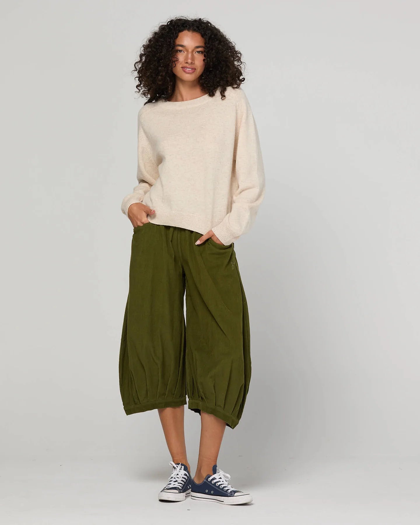 Woman wearing the Cord Guru Pant in Olive Green, featuring a relaxed 3/4 balloon-leg fit in soft cotton cord with a cool-toned khaki finish.