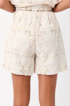 Cream broderie cotton shorts with an elasticized waist, zip closure, and front pockets, perfect for beachside casual wear.