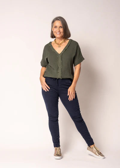 V-neck linen and cotton top with delicate lace detailing and subtle front fringing, relaxed fit, lightweight natural fabric.