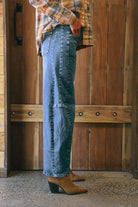Mid-blue denim barrel-leg jeans with a relaxed fit, cuffed hem, side panel detailing, contrast stitching, and 5-pocket design.