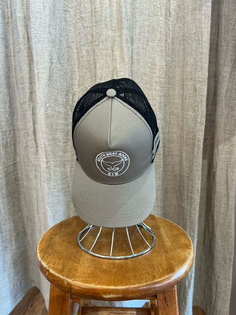 Rocks Hat in tan and black featuring a whale tail design on the front, snapback closure, and breathable mesh sides for a comfortable, adjustable fit.