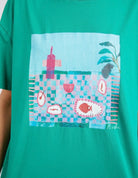 The Goodness Green Island In The Sun Tee by Elm is available at Rawspice Boutique.