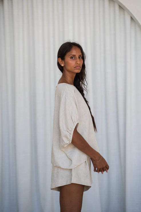 The Lily Pilly Tina Top in soft oatmeal linen is designed with a relaxed silhouette, lightweight feel, and natural textured weave.