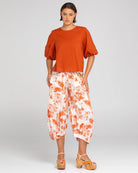 A woman modelling the Ava Puffed Sleeves Top in Mecca Orange by Boom Shankar