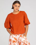 A woman modelling the Ava Puffed Sleeves Top in Mecca Orange by Boom Shankar