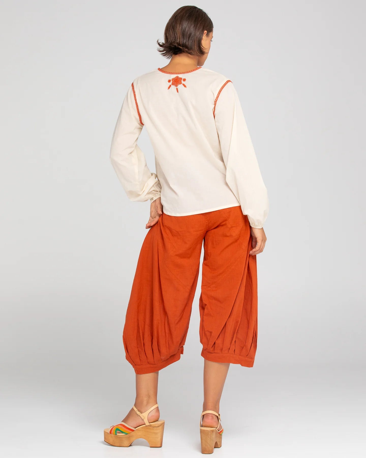 A woman modelling Boom Shankar Guru Pants in Mecca Orange from behind