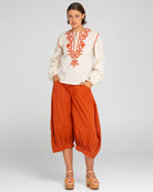 A woman modelling Boom Shankar Guru Pants in Mecca Orange