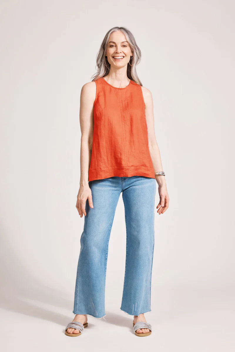A relaxed, coral-coloured 100% linen tank top featuring exposed shoulders, contrast decorative topstitching, and a soft A-line silhouette. The design includes a wide cuffed hem and a button closure at the back neck, giving the lightweight, breathable top an effortlessly refined look