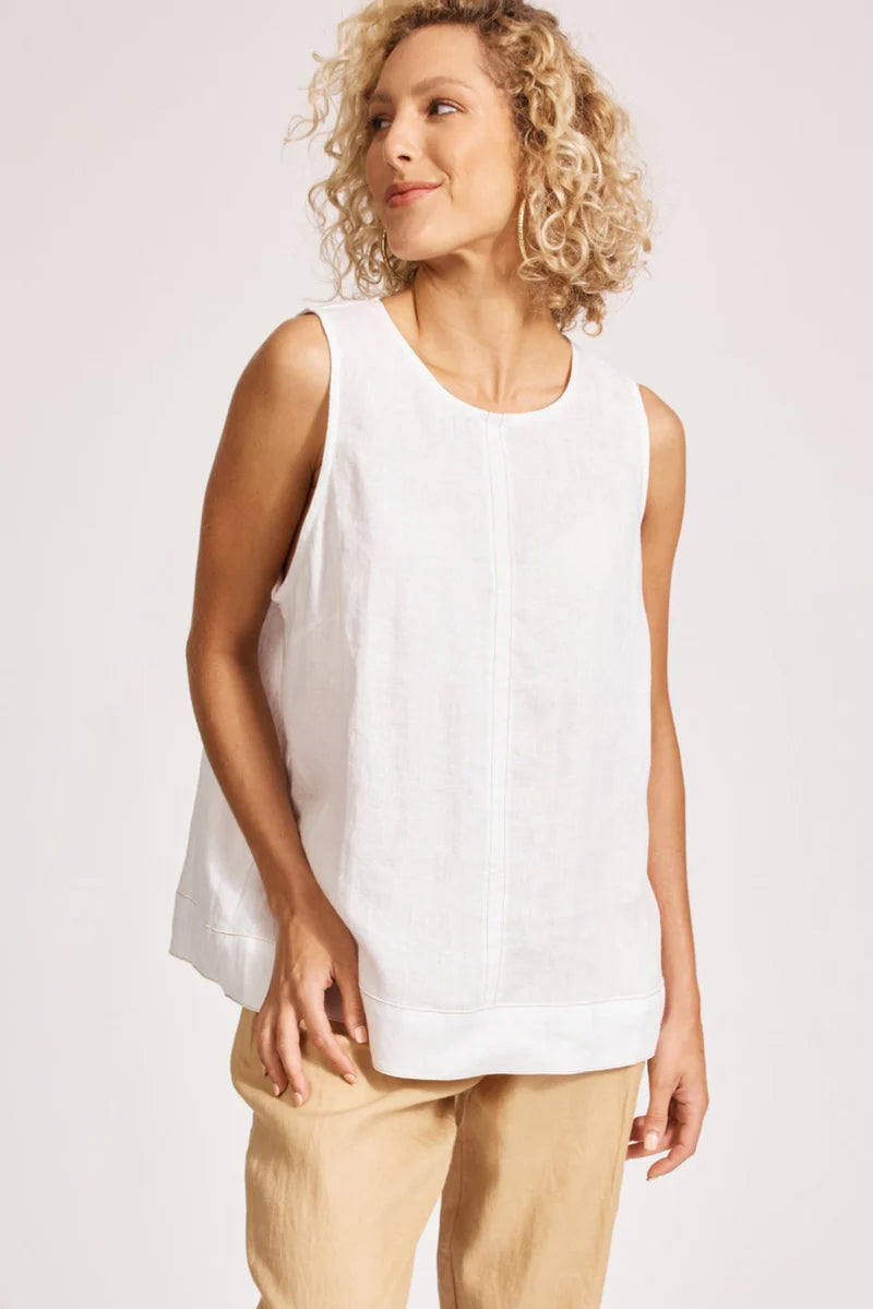 A relaxed, white 100% linen tank top featuring exposed shoulders, contrast decorative topstitching, and a soft A-line silhouette. The design includes a wide cuffed hem and a button closure at the back neck, giving the lightweight, breathable top an effortlessly refined look