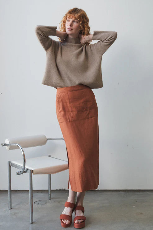 Nadi Linen Skirt in Cajun – A stylish, straight-cut linen skirt in a warm Cajun hue. Features oversized front pockets, side splits for ease of movement, and an elasticated back waistband for a comfortable, flattering fit.