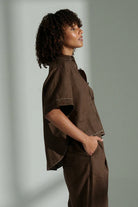 Nika linen shirt in chocolate with relaxed short sleeves, contrast stitching, front pocket, high-low curved hem and corozo buttons.
