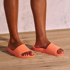 A pair of peach arch support slides with contoured footbeds and wide straps, designed for comfort and all-day wear.