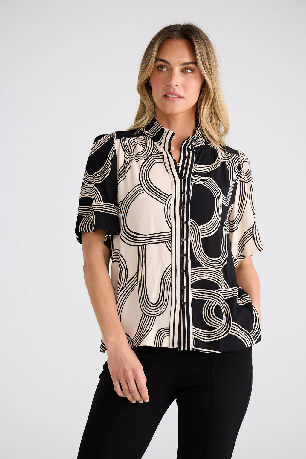 Penelope Top featuring a high-neck collar, self-covered button front with rouleau loops, flared short sleeves, and a relaxed, gathered silhouette with side splits.
