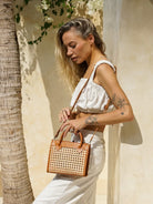 Prague Clutch in black and tan featuring natural rattan weaving with genuine leather accents in a sleek summer-ready design.