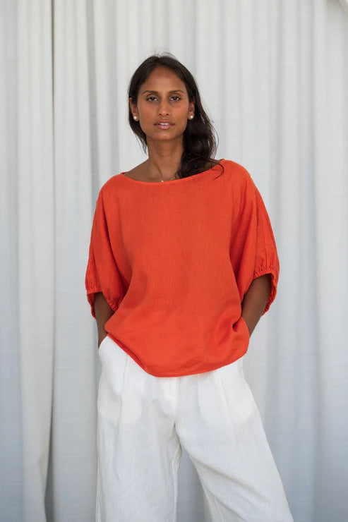 The Lily Pilly Tina Top in vibrant orange spritz is designed with a relaxed silhouette, lightweight feel, and natural linen textured weave.