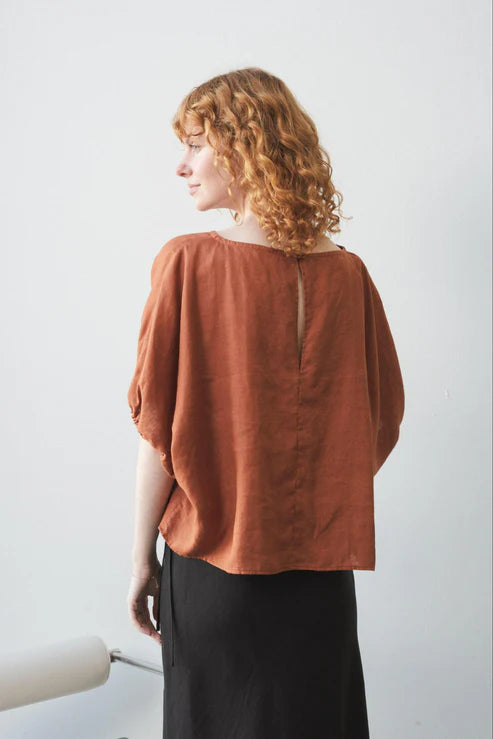 Tina Linen Top in Cajun – A breathable, lightweight linen top in a warm, earthy Cajun hue. Designed with a relaxed fit, short sleeves, and a button-down front for effortless, everyday styling.