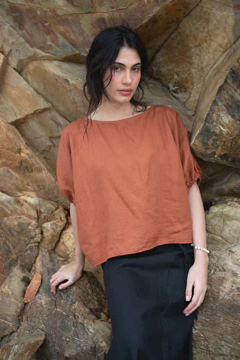 Tina Linen Top in Cajun – A breathable, lightweight linen top in a warm, earthy Cajun hue. Designed with a relaxed fit, short sleeves, and a button-down front for effortless, everyday styling.