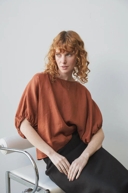 Tina Linen Top in Cajun – A breathable, lightweight linen top in a warm, earthy Cajun hue. Designed with a relaxed fit, short sleeves, and a button-down front for effortless, everyday styling.