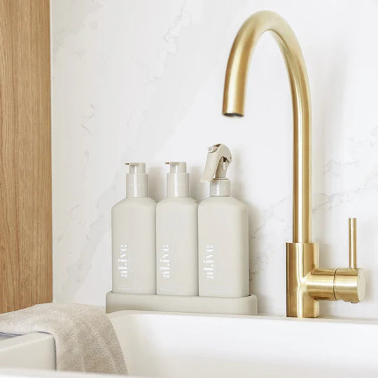 The Alive Kitchen Trio Set, featuring Dishwashing Liquid and Bench Spray in Lemon & Pomegranate scent, and Hand Wash in Watermelon & Lime scent, all neatly arranged in a sleek, custom tray. The white bottles with vibrant, fresh-colored labels are displayed on a clean countertop, exuding a refreshing and vibrant aesthetic with fruity, citrus-inspired fragrances.