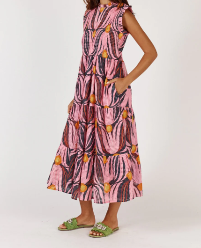 A feminine midi dress in a soft textured Tulip print, made from a cotton-nylon blend. The design features a round neckline with a delicate frill, sleeveless armholes with matching frill trim, and a shirred bodice that contours the figure. A flowing A-line skirt falls to mid-calf, complemented by functional pockets for added ease. The dress offers a relaxed, elegant fit suitable for a variety of occasions