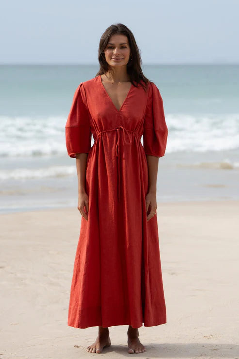 Vida Linen Dress in Hibiscus – A flowy midi-to-maxi linen dress in a vibrant hibiscus hue. Features an adjustable front-tie waistline, oversized bell sleeves, side pockets, and premium French seams for a refined finish.